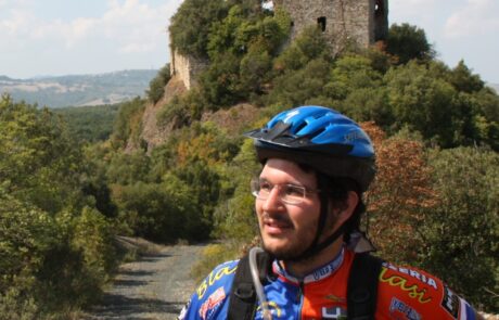 Biking Toskana Mountainbiker vor Burgruine und Wald